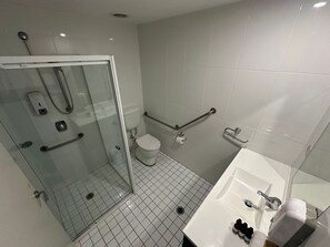 A modern bathroom with a glass shower enclosure, a white toilet, and a sink with a mirror.