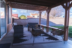 Une terrasse extérieure aménagée avec des meubles en osier, une pergola en bois et une vue sur un quartier résidentiel.