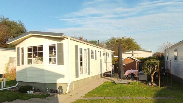 A single-story mobile home with a front porch and a small backyard. - ZP 468 - Camping de Zandput (Vrouwenpolder)
