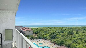 Ein Balkon mit Blick auf einen Strand und ein Schwimmbad.