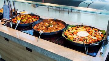 A buffet with various dishes, including seafood and salads, displayed on a counter with a digital clock.