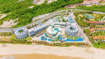 Un resort con varias piscinas, un edificio circular central y una zona de playa.