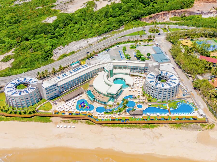 Un resort con varias piscinas, un edificio circular central y una zona de playa.