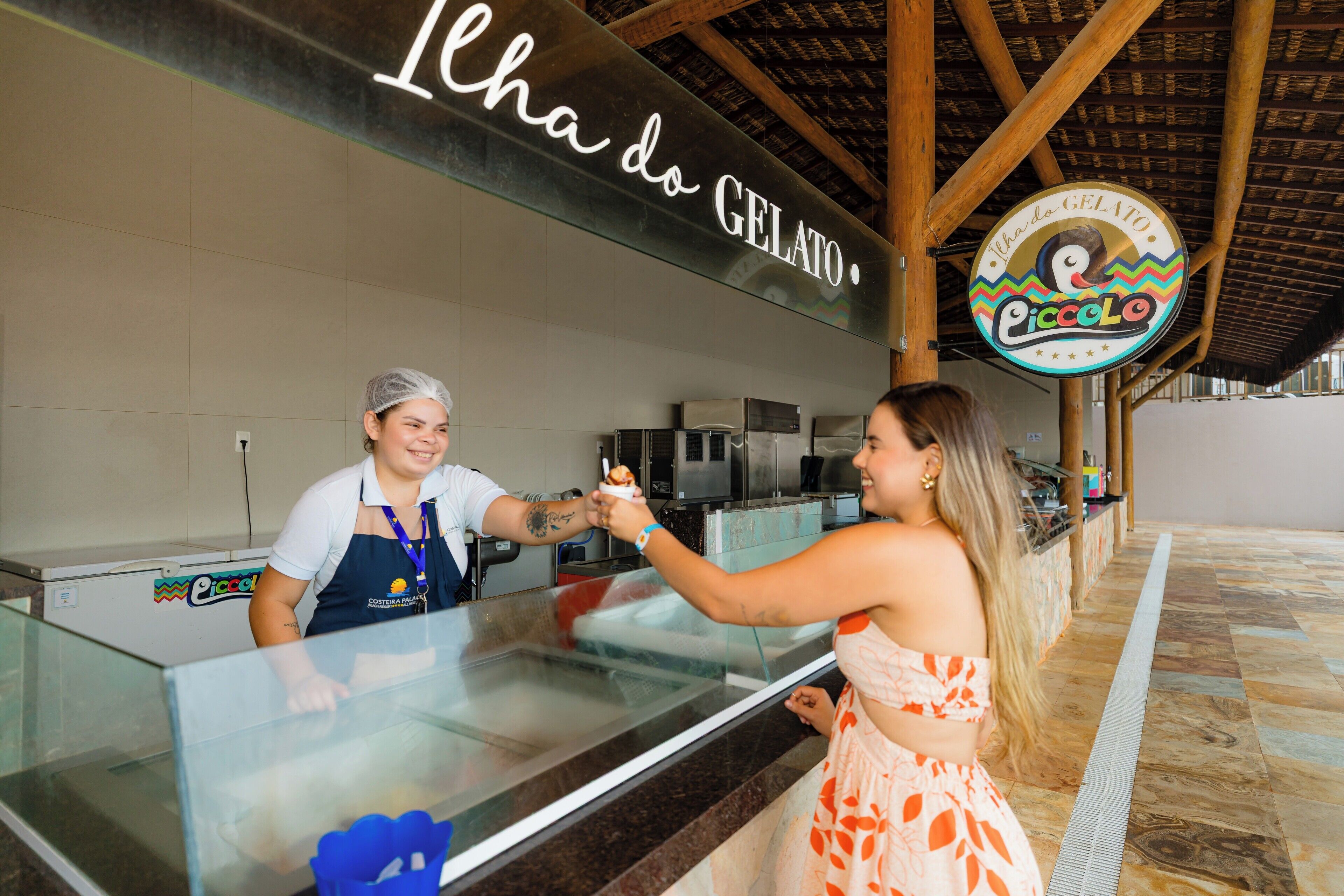 A gelato stand with a sign reading "Icha do GELATO" and a logo for "Piccolo Gelato".