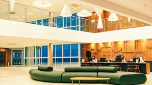 A modern lobby with a green sofa, a wooden reception desk, and a glass entrance.