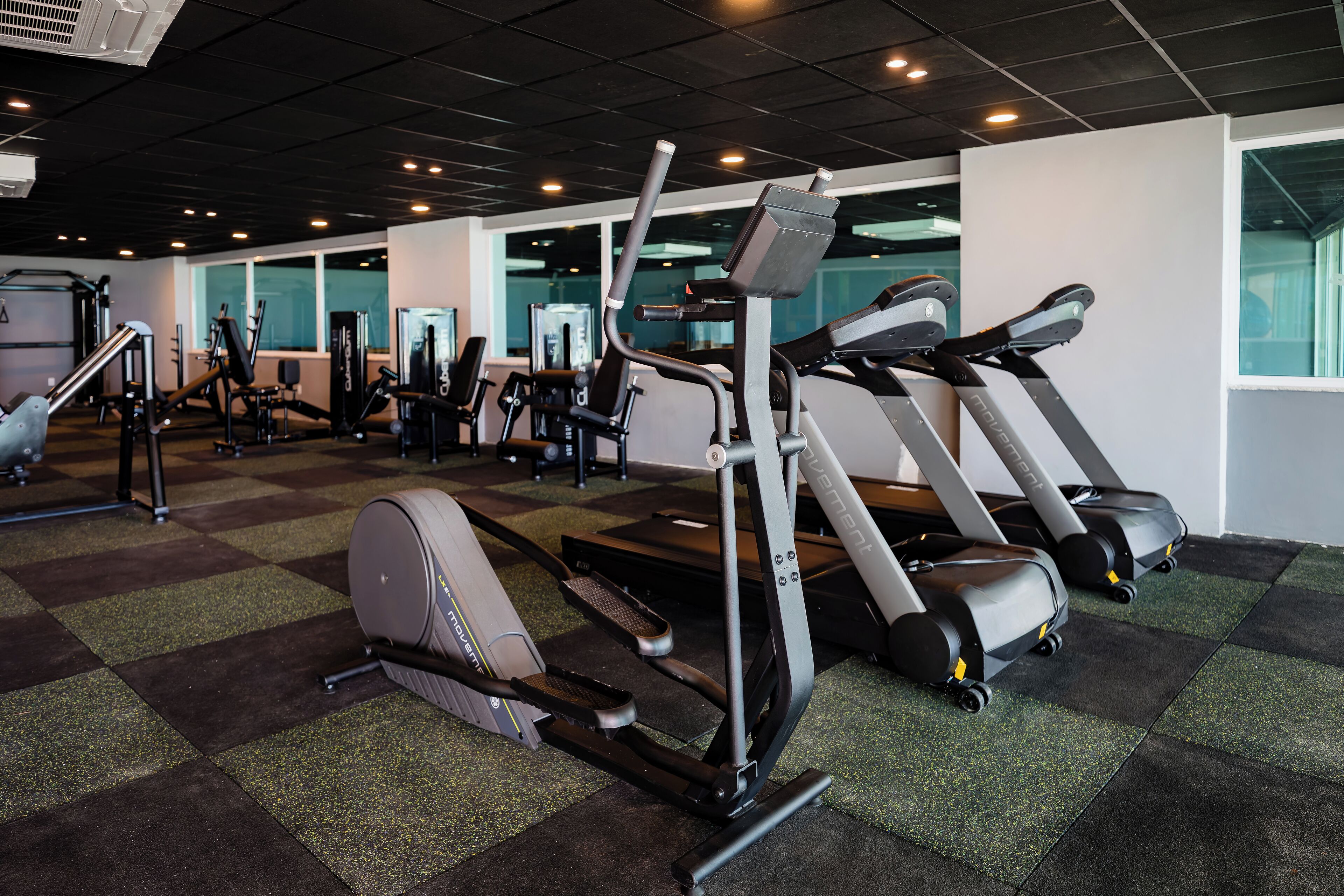 Une salle de sport équipée de tapis de course, de vélos elliptiques et d’appareils de musculation.