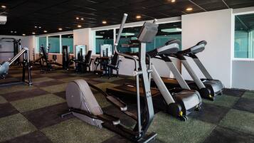 Une salle de sport équipée de tapis de course, de vélos elliptiques et d’appareils de musculation.