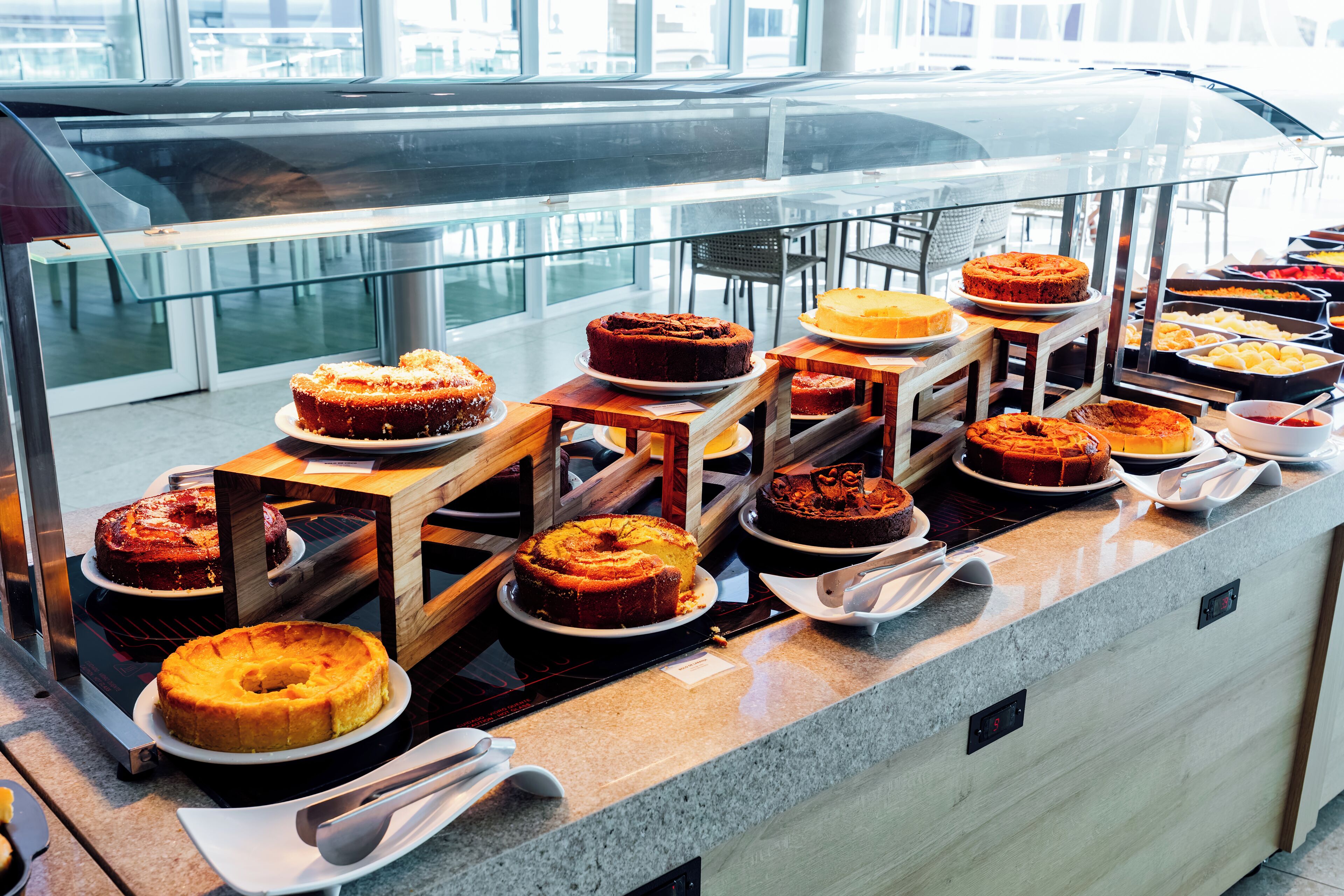 Buffet com diversos bolos e doces dispostos em suportes e pratos de madeira.