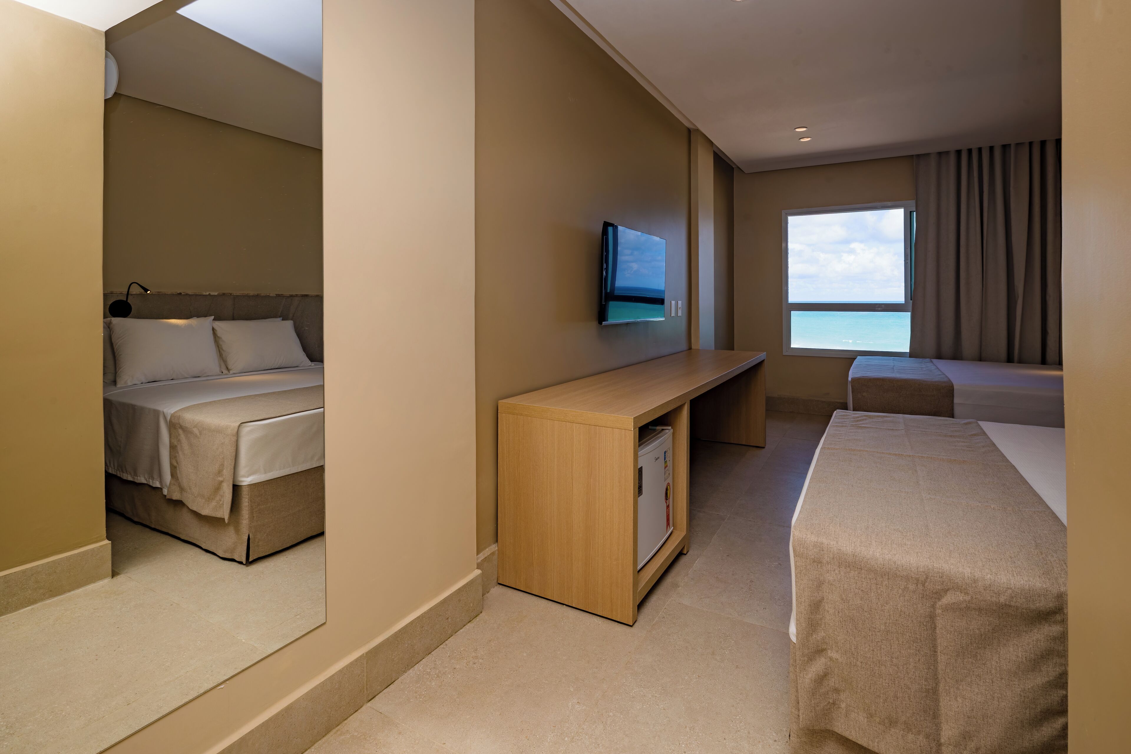 A hotel room with a bed, a desk, a television, and a window with a view.