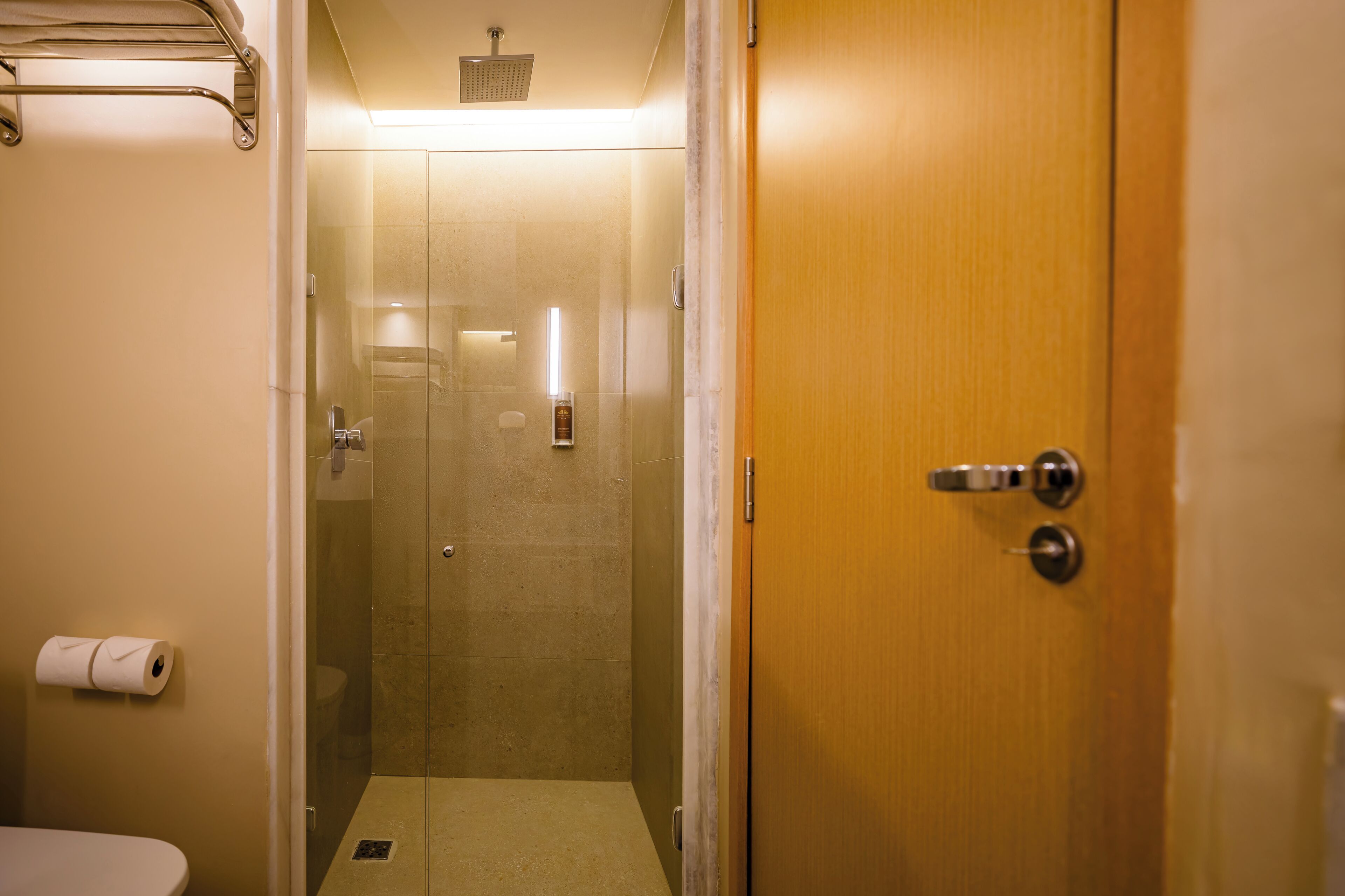 Un baño con inodoro, cabina de ducha y puerta de madera.