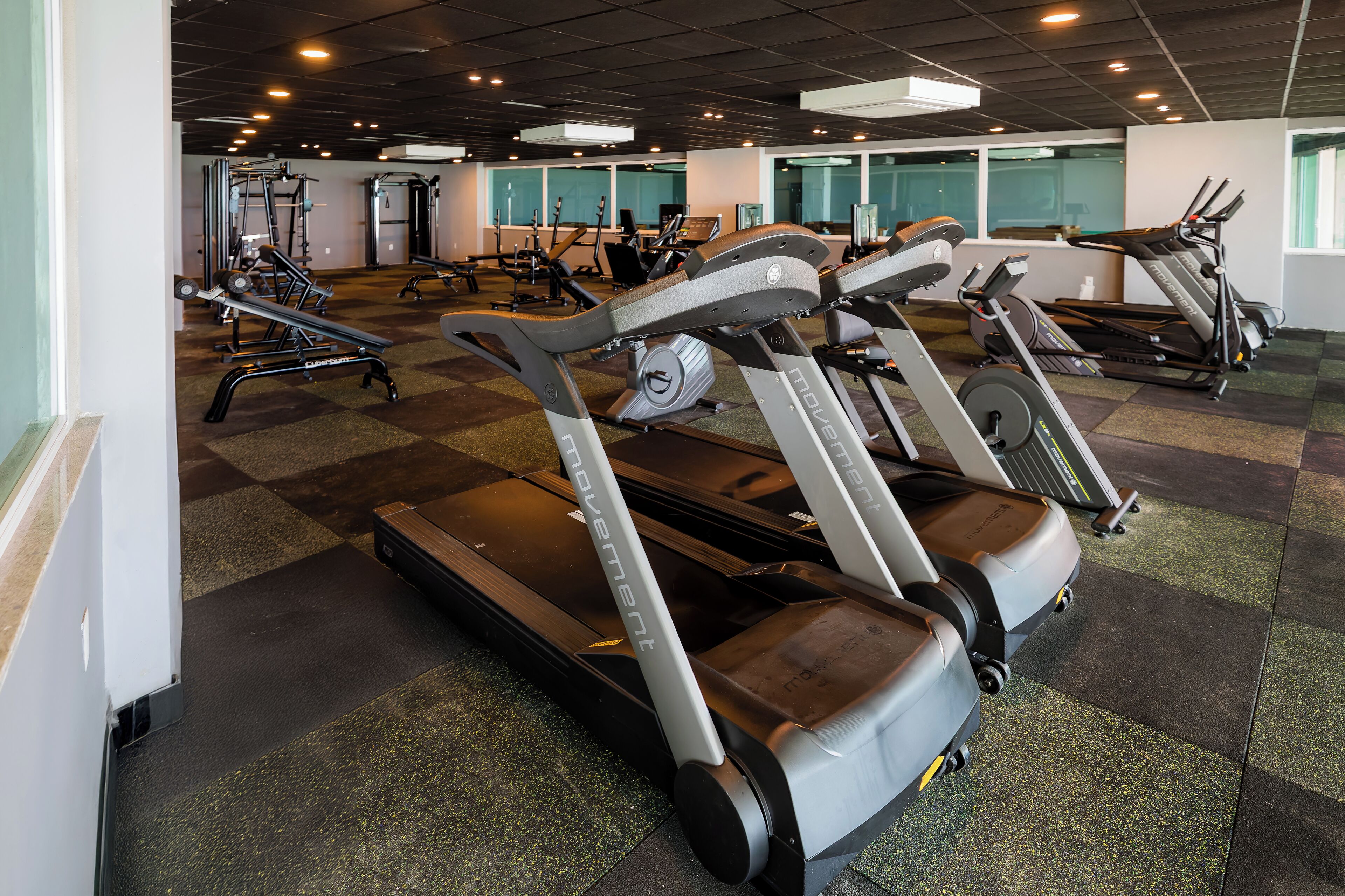 Un gimnasio con cintas de correr, bicicletas estáticas y máquinas de pesas.