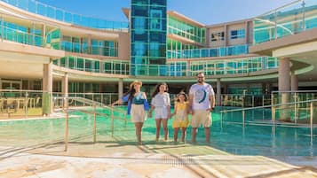 A modern hotel with a glass atrium, a pool area, and multiple levels of balconies.