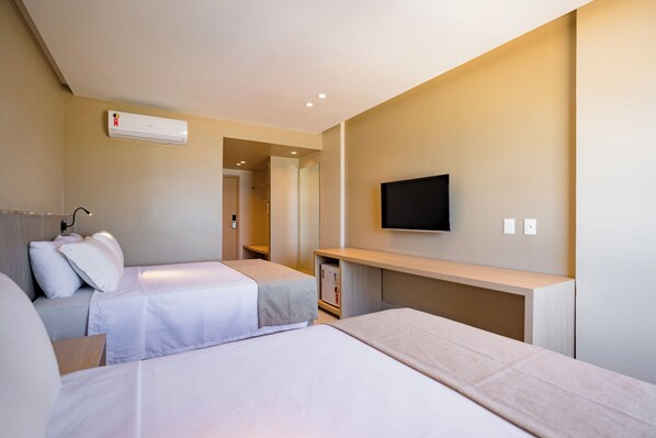 Une chambre d’hôtel avec deux lits, un téléviseur fixé au mur et un appareil de climatisation.