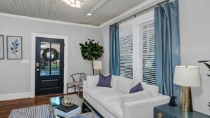 A living room with a white sofa, a coffee table, a lamp, and a plant. - The Indigo - 2BR w/Hot Tub & Outdoor Space (Columbia)