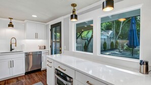 A modern kitchen with white cabinetry, stainless steel appliances, and pendant lighting. - The Indigo - 2BR w/Hot Tub & Outdoor Space (Columbia)