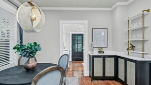 A modern kitchen with a black and white color scheme, featuring a round chandelier, a potted plant, and a built-in wine rack. - The Indigo - 2BR w/Hot Tub & Outdoor Space (Columbia)