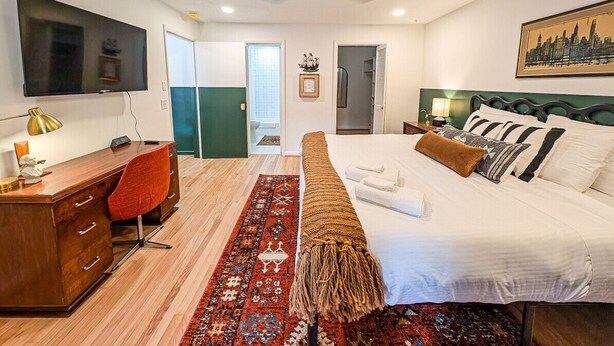 Una habitación de hotel moderna con cama, escritorio, silla y televisor.