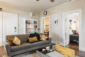 A living room with a grey sofa, a coffee table, and a bookshelf.