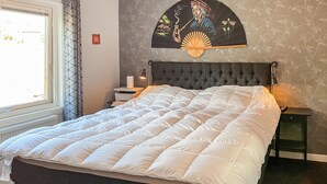 A bedroom with a large bed, a bedside table with a lamp, a wall-mounted fan, and a window with curtains. - 4 bedroom lovely home in Sommen (Sommen)