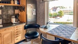 A kitchen with a laptop on a table, a refrigerator, and a window with a view of houses. - 4 bedroom lovely home in Sommen (Sommen)