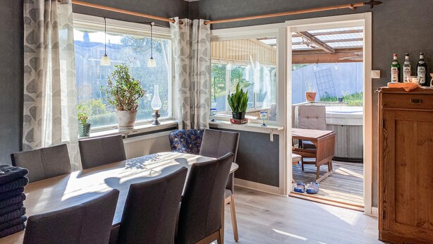 A cozy dining area with a table and chairs, large windows with curtains, and a view of the backyard. - 4 bedroom lovely home in Sommen (Sommen)