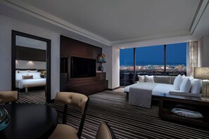 Une chambre d’hôtel avec un lit, un canapé, une télévision, une table à manger et une vue sur le paysage urbain.