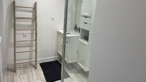 Kylpyhuone, jossa on puinen tikapuu, valkoinen pesuallas ja kaappi.