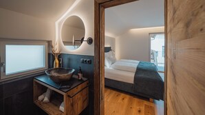A modern bathroom with a wooden vanity, a large round mirror, and a vessel sink.