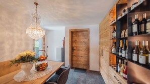 A dining area with a wooden table, a vase of flowers, a chandelier, and a wine rack.