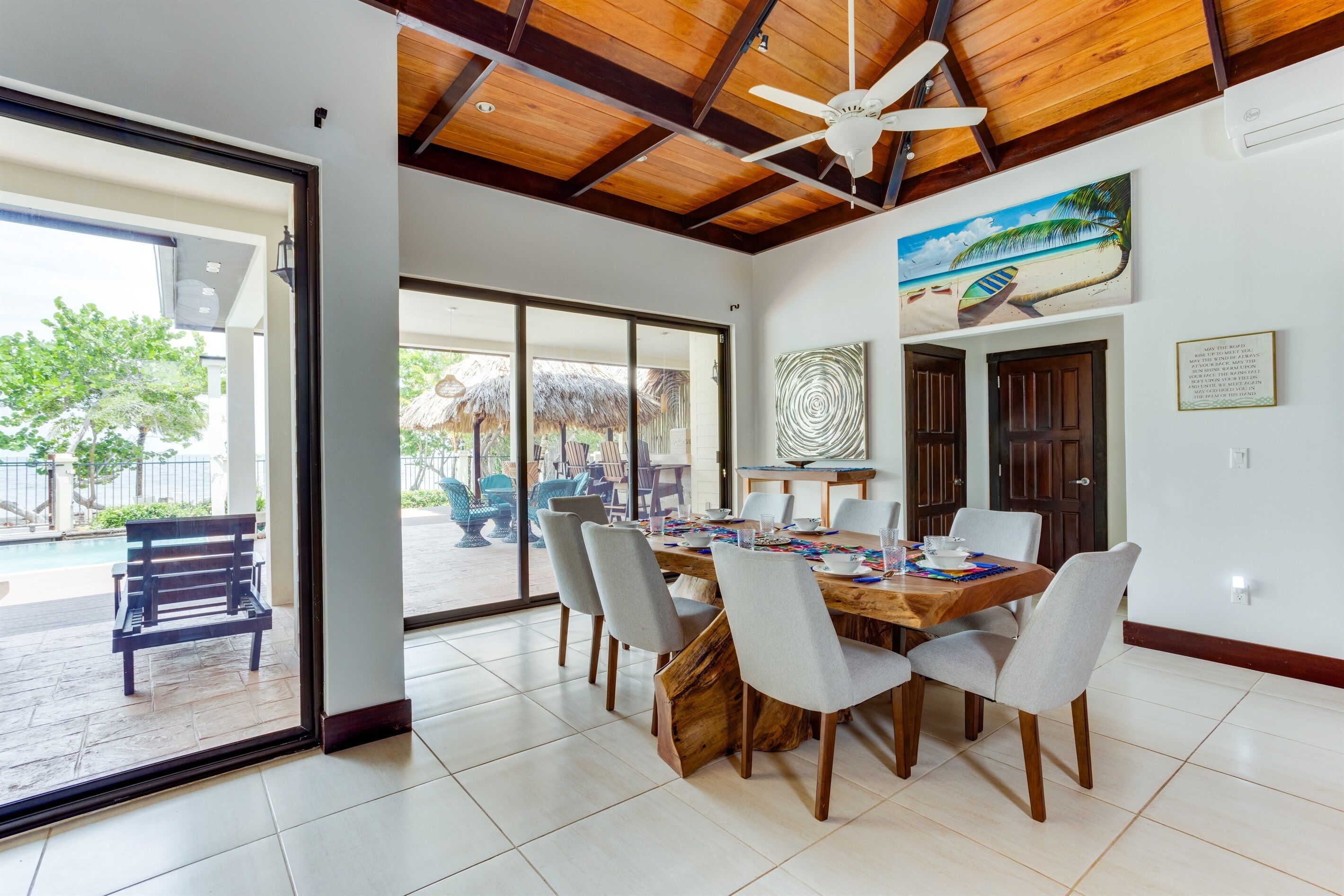 A dining area with a wooden table and chairs, a ceiling fan, and a view of the outside patio.
