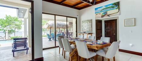 A dining area with a wooden table and chairs, a ceiling fan, and a view of the outside patio.
