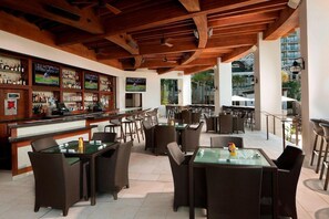 Een terras met een bar, rieten meubels en een houten plafond.