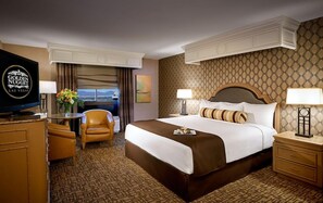 Une chambre d’hôtel avec un grand lit, un bureau avec une télévision, une chaise et une vue sur la ville.