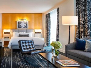 A hotel room with a bed, a desk, a chair, a lamp, and a vase with flowers. - 2 Connecting Suites at a 4.5⭐️ Hotel (Chicago)