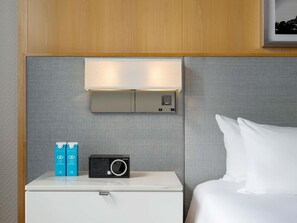 A hotel room with a bed, a bedside table with a radio, and a wall-mounted light fixture. - 2 Connecting Suites at a 4.5⭐️ Hotel (Chicago)
