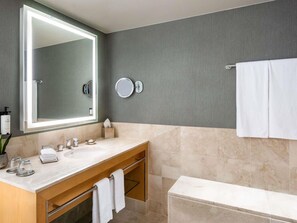 Une salle de bain moderne avec un grand miroir, deux lavabos, un meuble-lavabo et une baignoire.