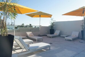 A rooftop lounge area with white lounge chairs and yellow umbrellas. - 2 Connecting Suites at a 4⭐️ Hotel (Miami Beach)