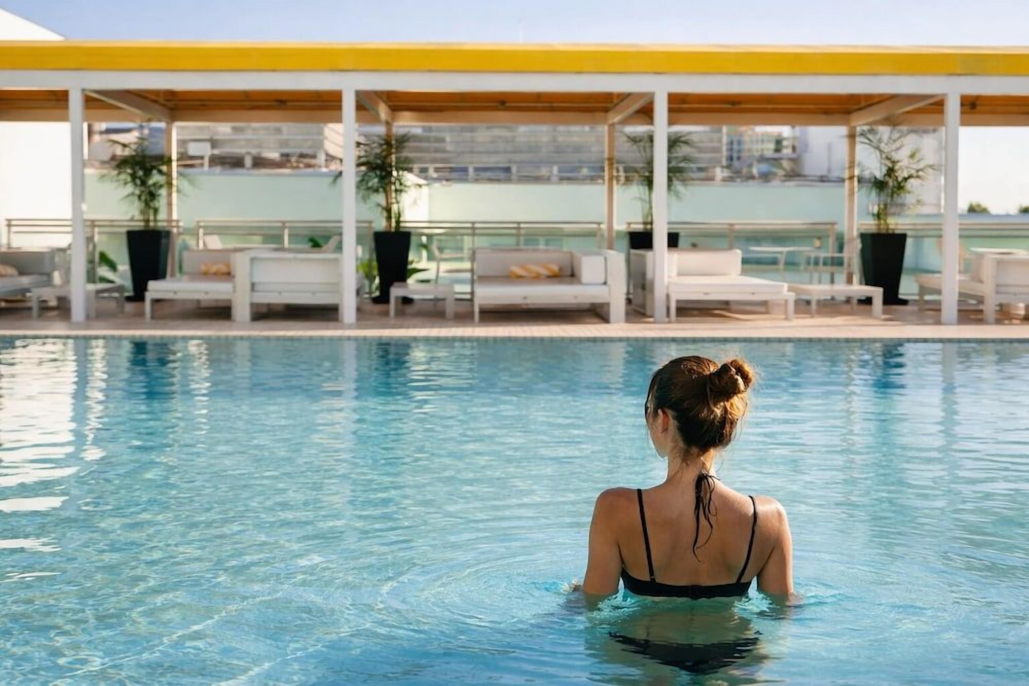 A pool area with lounge chairs and a covered seating area.
