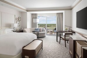 Une chambre d’hôtel avec un grand lit, un canapé, un bureau et une télévision. Elle dispose d’un balcon avec vue sur le paysage.