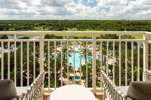 A balcony with a view of a swimming pool and surrounding greenery.