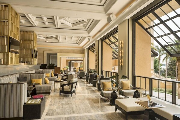 A spacious lobby with a high ceiling, large windows, and a variety of seating arrangements.