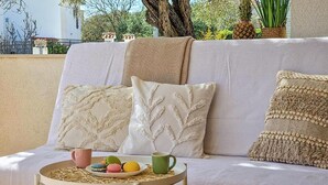 Un canapé agrémenté de coussins décoratifs, une petite table avec un set de table et une assiette remplie de macarons colorés.