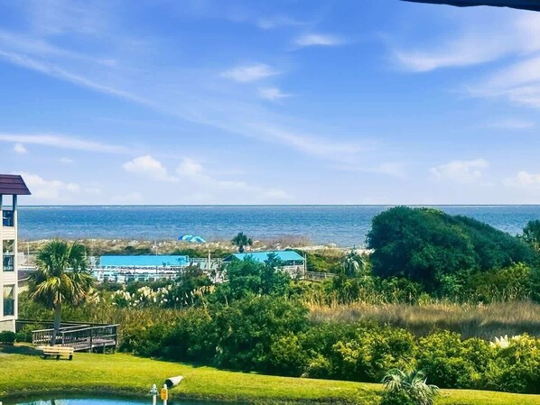 A view of a coastal area with a clear sky, a body of water, and a building with a blue roof.
