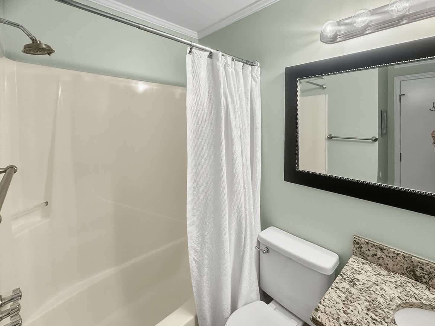 Ein Badezimmer mit Duschkabine, weißer Toilette und einer Arbeitsplatte aus Granit.