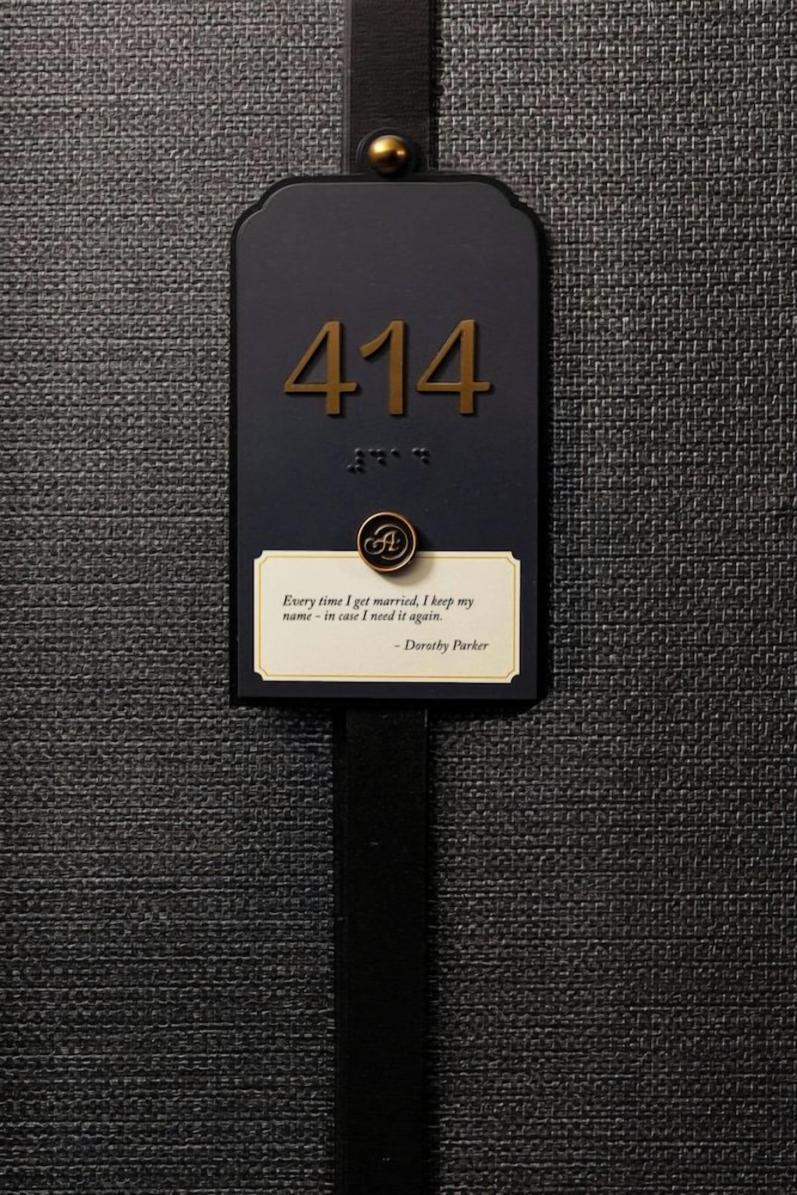 A black address tag with the number 414 and a quote by Dorothy Parker.