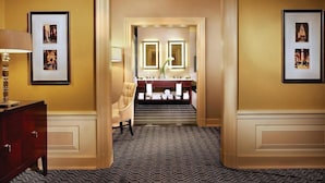 A hotel hallway with a mirror, framed pictures, a chair, and a vanity with a mirror. - 2 Connecting Suites at a 4⭐️ Hotel (New York)