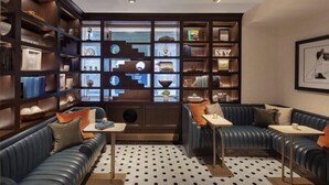 Una biblioteca moderna con sofás de cuero, piso estampado y estanterías llenas de libros y objetos decorativos.
