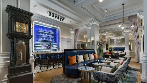 A bar area with a blue-lit shelf, a vintage clock, and seating with round tables and chairs. - 2 Connecting Suites at a 4⭐️ Hotel (New York)