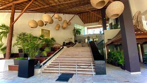 Un hall d’entrée spacieux, agrémenté d’un escalier, de plantes en pot et de lampes suspendues en osier.
