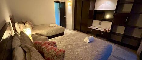 A hotel room with a large bed, a bedside table, a wardrobe, and a bathroom door.